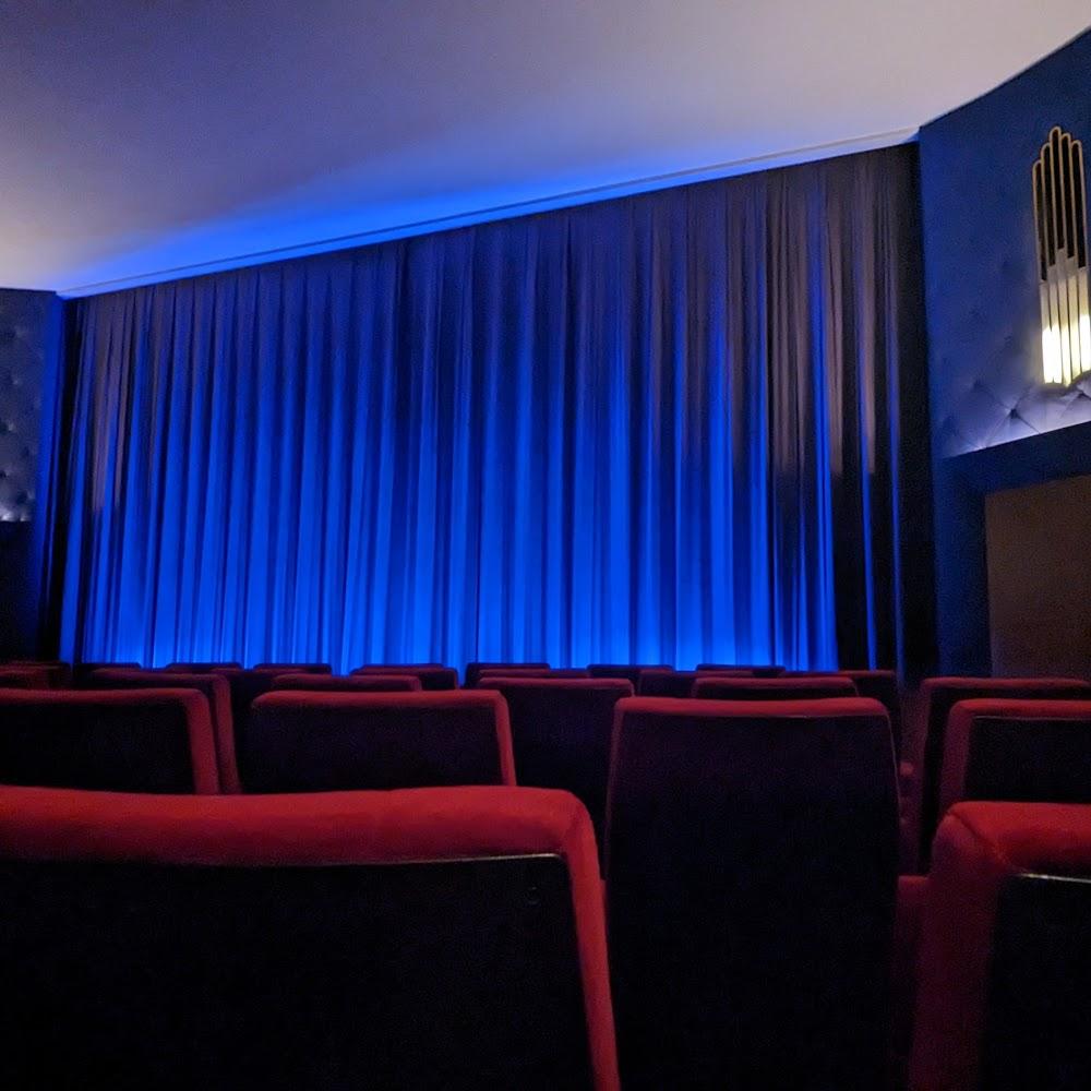 Empty theater seats with a blue screen curtain.